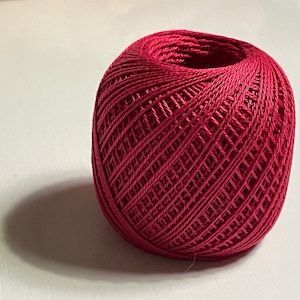 May include: A ball of deep red yarn, wound into a neat circle.