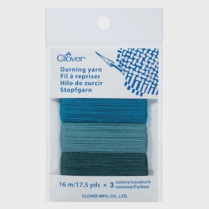 May include: A package of Clover darning yarn in shades of blue. The package contains three spools of yarn, each a different shade of blue. The package reads "Darning yarn" and "16 m/17.5 yds x 3 colors".