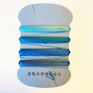 May include: A card with four spools of blue and green embroidery floss. The card is labeled "金亀糸業株式会社" in Japanese.