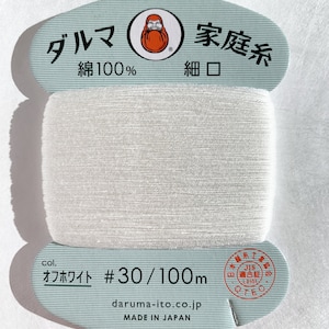 May include: A white spool of thread labeled "Daruma" with a red Daruma doll logo. The label also says "Family Thread" in Japanese, "Cotton 100%", "Fine Mouth", "Off White", "#30/100m", "daruma-ito.co.jp", and "Made in Japan".