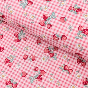 May include: A roll of pink and white gingham fabric, adorned with a charming pattern of strawberries and daisies. The strawberries are a vibrant red with green leaves, and the daisies feature white petals and yellow centres. The fabric is folded, revealing the pattern.