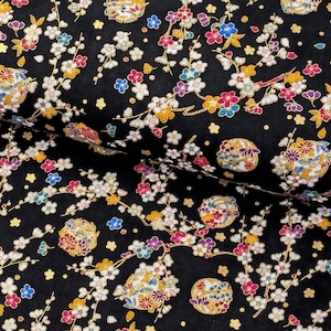 May include: A black fabric featuring a dense pattern of small white, pink, blue, and yellow cherry blossom flowers on thin branches. The design includes circular motifs filled with intricate floral details and gold metallic accents throughout.