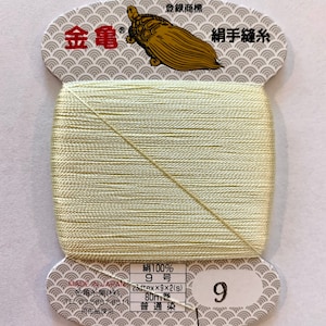 May include: A spool of pale yellow silk thread with a label that reads "Silk 100%, 9 Number, 23dtex x 9 x 2 (s), 80m, Ordinary Dye, 9". The label also features a turtle logo and the text "Registered Trademark, Gold Turtle, Hand Sewing Thread".