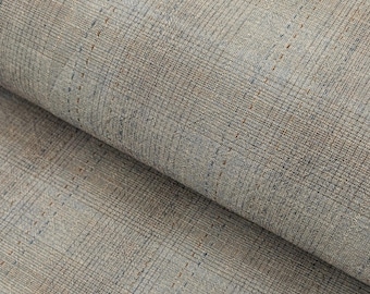 May include: Close-up of a textured fabric with a plaid pattern. The fabric is primarily a muted blue-gray color, with subtle brown and darker blue lines forming the plaid. The fabric is folded over, revealing its layered texture.