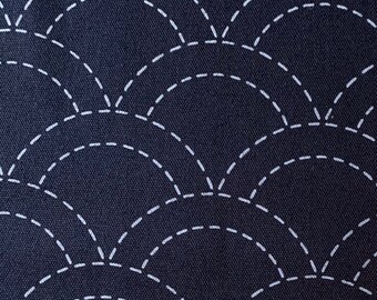 May include: A dark blue fabric with a white stitched pattern of repeating arcs. The arcs are made up of a series of small dashes.