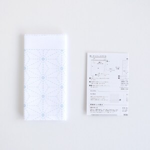 Puede incluir: Una tela blanca con un patr&oacute;n geom&eacute;trico azul, una hoja de instrucciones impresa con texto japon&eacute;s y diagramas para un proyecto de artesan&iacute;a.