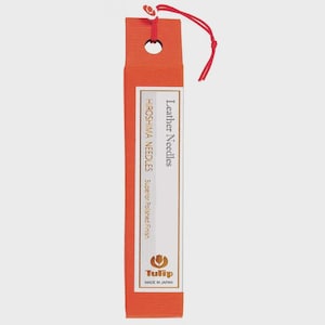 May include: An orange package of "Leather Needles" with the text "Hiroshima Needles" and "Superior Polished Finish". The package has a red string attached and a "Tulip" logo, with "Made in Japan" printed below.