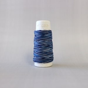 May include: A spool of blue and white striped thread with the word "cosmo" printed on the side.