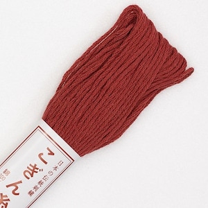 May include: A skein of red-brown embroidery floss with a white label featuring Japanese text. The floss is tightly wound and appears soft. The label has Japanese text and a small logo.