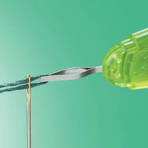 May include: A green plastic needle threader with a metal loop. The threader is threading a green embroidery floss through a gold eye needle.