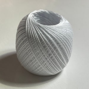 May include: A white ball of yarn, wound tightly in a spiral pattern.