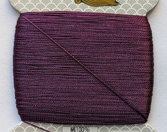 May include: A spool of purple silk thread with a label that reads "絹100% 9号 23dtex×9×2(s) 80m巻 普通染" and "金亀糸業(株) 03-5687-851" and "MADE IN JAPAN" and "絹手縫糸" and "185".