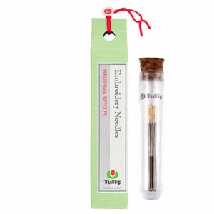 May include: A glass tube filled with embroidery needles, labeled "Tulip" and "Hiroshima Needles". The tube is capped with a cork top and has a red string tied around it.