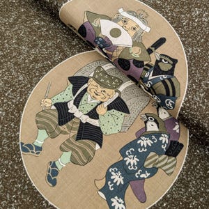 May include: A decorative fabric with a repeating pattern of small, light-colored flecks. The fabric features a circular design with illustrations of Japanese figures in traditional clothing. The figures are in shades of green, blue, purple, and brown.