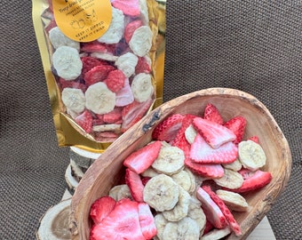May include: A gold resealable bag filled with dried fruit snacks. The bag is labeled "RK Frog dried goodies organic strawberries & bananas slices keep it zipped keep it crisp". The fruit snacks are a mix of dried banana slices and dried strawberry slices. The fruit snacks are in a wooden bowl.