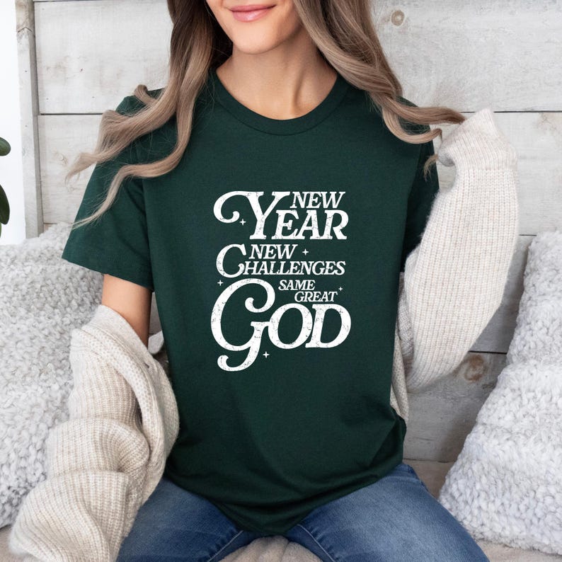 May include: A dark green t-shirt with a white graphic that reads "New Year New Challenges Same Great God".
