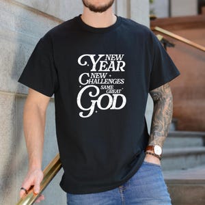 May include: Black t-shirt with a white graphic that reads "New Year New Challenges Same Great God".