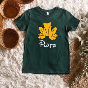 May include: A dark green t-shirt with a cartoon image of Pluto the dog in a sitting position. The text "Pluto" is printed in white below the image.