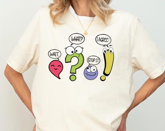 May include: A white t-shirt with a graphic of cartoon punctuation marks with faces. The punctuation marks are a comma, question mark, period, and exclamation point. The comma says "Wait", the question mark says "What?", the period says "Stop it", and the exclamation point says "I agree!"