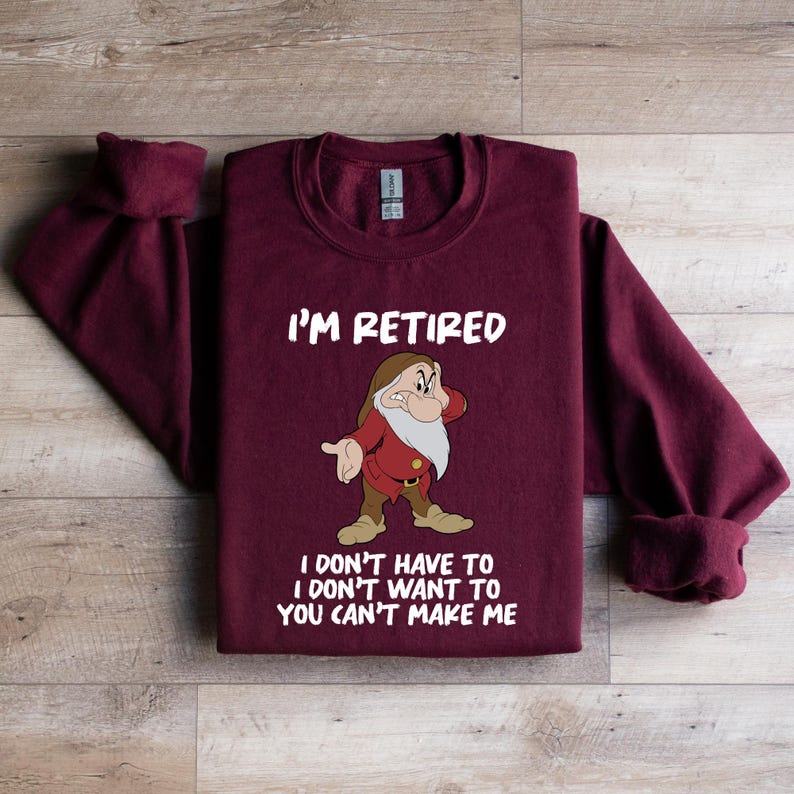 May include: A maroon sweatshirt with the text "I'M RETIRED" above a cartoon image of a dwarf. Below the image, the text reads "I DON'T HAVE TO I DON'T WANT TO YOU CAN'T MAKE ME".
