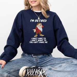 May include: Navy blue sweatshirt with the text "I'M RETIRED" and a cartoon image of a dwarf. Below the image, the text reads "I DON'T HAVE TO I DON'T WANT TO YOU CAN'T MAKE ME".