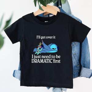 Puede incluir: Camiseta negra con un personaje azul Stitch de Lilo & Stitch. El texto en la camiseta dice "I'll get over it I just need to be DRAMATIC first".