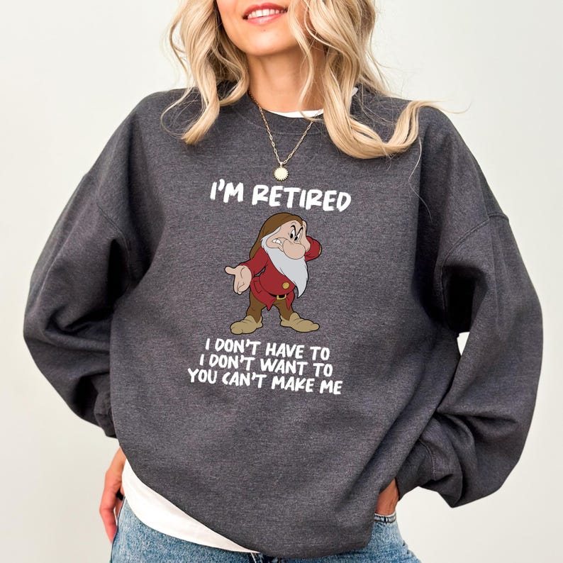 May include: Dark gray sweatshirt with the text "I'M RETIRED" and a cartoon image of a grumpy dwarf. Below the image, the text reads "I DON'T HAVE TO I DON'T WANT TO YOU CAN'T MAKE ME". The sweatshirt has a crew neck.