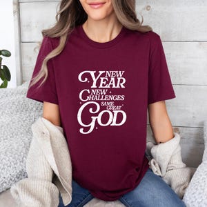 May include: A maroon t-shirt with a white graphic that reads "New Year New Challenges Same Great God".