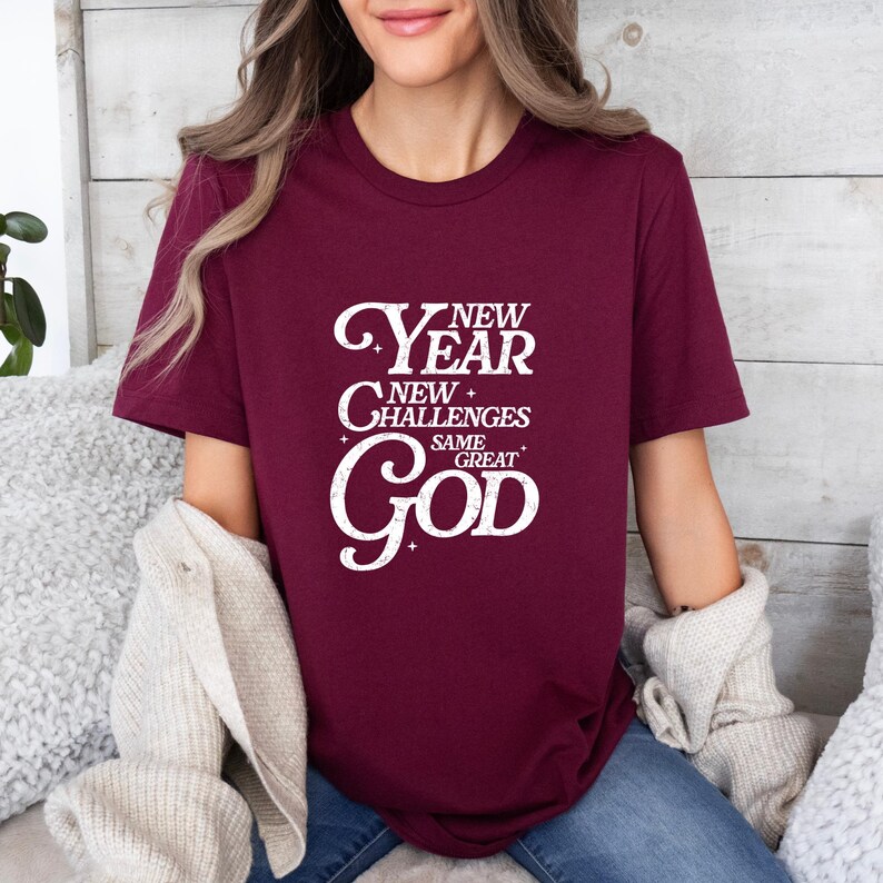 May include: A maroon t-shirt with a white graphic that reads "New Year New Challenges Same Great God".