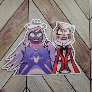 以下が含まれることがあります： 驚いた表情の2人の漫画のキャラクターが描かれたステッカー。1人のキャラクターは紫色の髪、翼、ハローを持っています。もう1人のキャラクターは赤いスーツを着ています。ステッカーは木製の背景にあります。