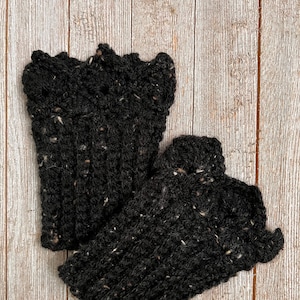 May include: A pair of black fingerless gloves with a flecked texture. The gloves are made of a soft, warm material and are perfect for keeping your hands warm in the winter.
