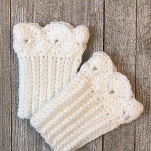 May include: A pair of white crocheted boot cuffs with a scalloped edge.