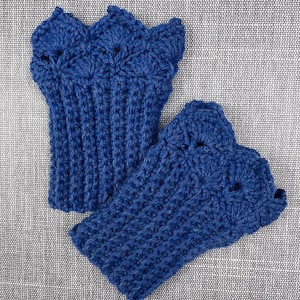May include: A pair of handmade, blue crochet fingerless gloves. The gloves feature a scalloped edge and a textured stitch pattern. The yarn appears to be a medium weight, and the gloves are displayed on a gray surface.
