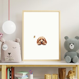May include: A framed print of a brown and white puppy dog with a butterfly in the background. The print is hanging on a white wall above a wooden shelf with a stuffed animal and books.