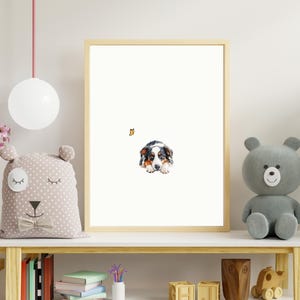 May include: A framed watercolor painting of a black, brown, and white puppy lying down and looking at the viewer. The puppy is in a white background with a small orange butterfly in the top left corner.