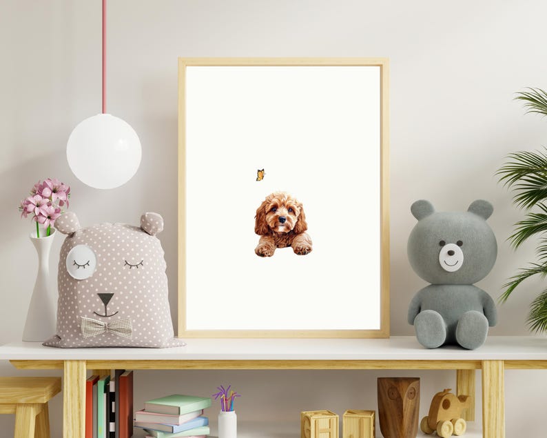 May include: A framed print of a brown and white dog with a butterfly above it. The print is hanging on a white wall above a wooden shelf with a stuffed animal and books.
