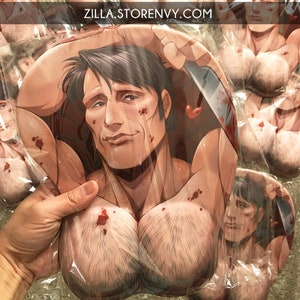 Puede incluir: Una alfombrilla de ratón con una ilustración impresa de una persona de pelo oscuro con pecho musculoso, sosteniendo un cuchillo con salpicaduras de sangre. El texto ZILLA.STORENVY.COM está impreso arriba. El diseño incluye áreas acolchadas.