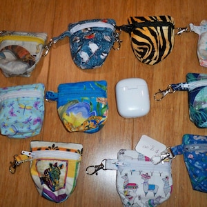 Op de afbeelding: Tien kleine ritsjes met verschillende kleurrijke patronen en ontwerpen. De tasjes hebben een lus om een ​​sleutelhanger of andere hardware aan te bevestigen. De tasjes zijn gemaakt van stof en hebben een ritssluiting.