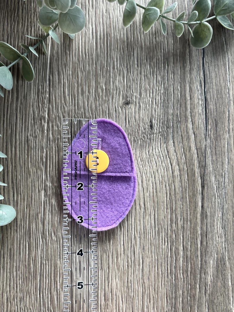 Op de afbeelding: Een paarse felt pouch met een gele knoopsluiting. De pouch is ongeveer 7,6 cm hoog.