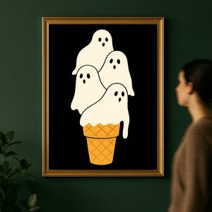 May include: A framed art print featuring a whimsical design. The artwork depicts four white ghost figures stacked on top of a waffle cone against a black background. The cone is a light orange color.
