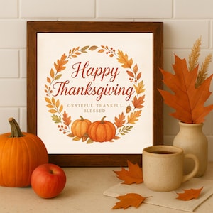 May include: A framed print with the words "Happy Thanksgiving" surrounded by a wreath of autumn leaves and pumpkins. A pumpkin, apple, mug, and vase with leaves are arranged on a surface, creating a festive fall scene.