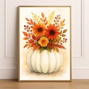 May include: Watercolor painting of a fall floral arrangement. The artwork features a white pumpkin vase filled with orange and yellow flowers, red berries, and fall foliage. The artwork is framed in a gold frame.