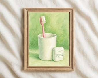 May include: A framed watercolor painting of dental hygiene items. A pink toothbrush stands in a white cup, with a container of dental floss beside it. The word "FLOSS" is printed on the floss container. The background is a soft green.