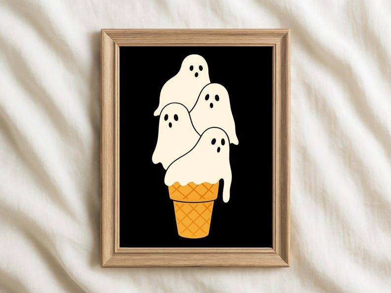 May include: A framed art print featuring a whimsical illustration of four ghost figures stacked on top of a waffle cone. The ghosts are white with black eyes and the cone is orange. The background is black.