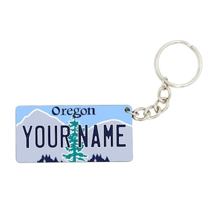 May include: A blue and white Oregon license plate keychain with the text "YOUR NAME" and a green pine tree graphic.