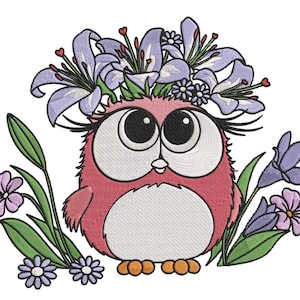May include: A cartoon owl with large eyes, a pink body, and a white belly. The owl is adorned with a floral crown of purple lilies and surrounded by green leaves and purple and pink flowers. The design has an embroidered appearance.