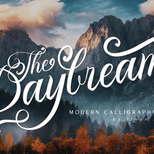 Peut inclure: Un paysage de montagne et de forêt sert de toile de fond au texte blanc en cursive "The Daydream". En dessous, le texte indique "Modern Calligraphy Font by Jinan Studio."