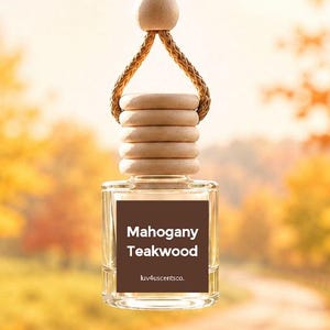 May include: A clear glass car air freshener bottle with a light wood cap and a braided hanging cord. The bottle features a square brown label with the white text Mahogany Teakwood and the smaller text luv4uscentsco. centered on the front surface.