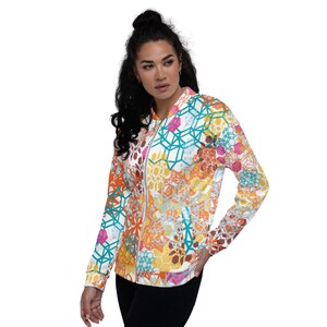 May include: A white bomber jacket with a colorful geometric pattern. The pattern features teal, orange, yellow, pink, and brown colors. The jacket has a zipper closure and a ribbed collar.