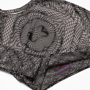 Pode incluir: Uma camisa bege de manga comprida com um padrão geométrico preto e branco. A camisa tem uma etiqueta que diz "birdmath" no canto inferior direito.